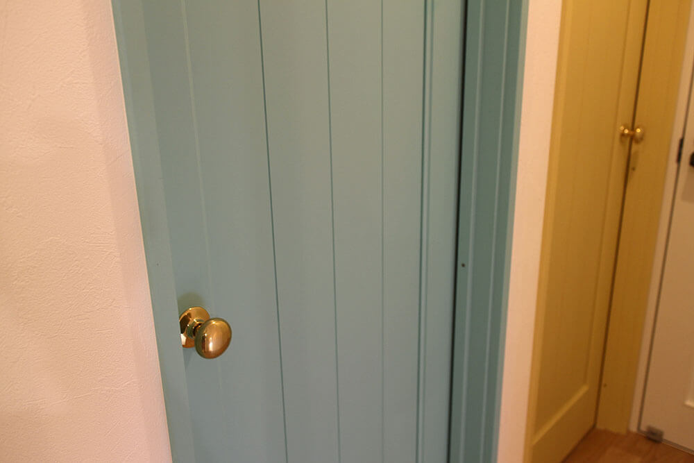 パステルカラーがかわいい、淡いブルーの室内ドアと真鍮ノブ